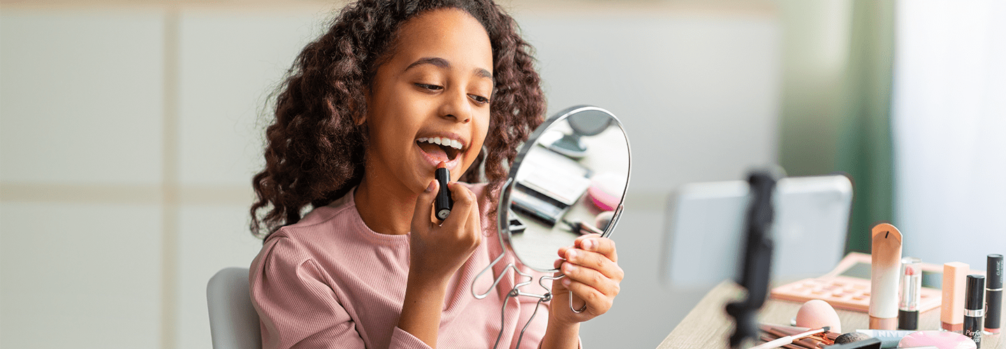 jong meisje met spiegel die lippenstift opdoet